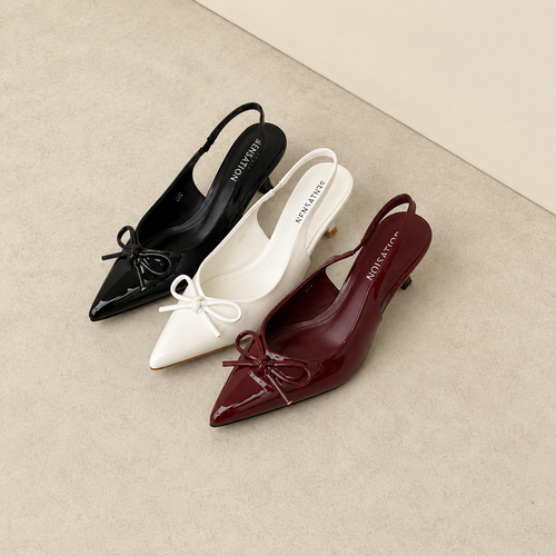 Three pairs of pointed-toe shoes in black, white, and burgundy on a beige surface.