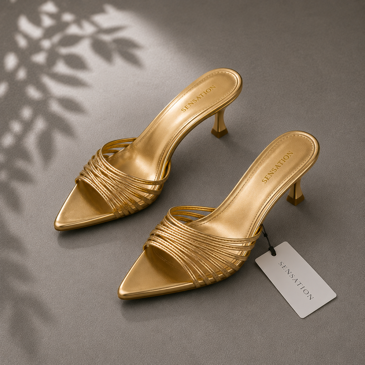 Pair of gold high-heeled shoes with a visible brand tag on a gray background